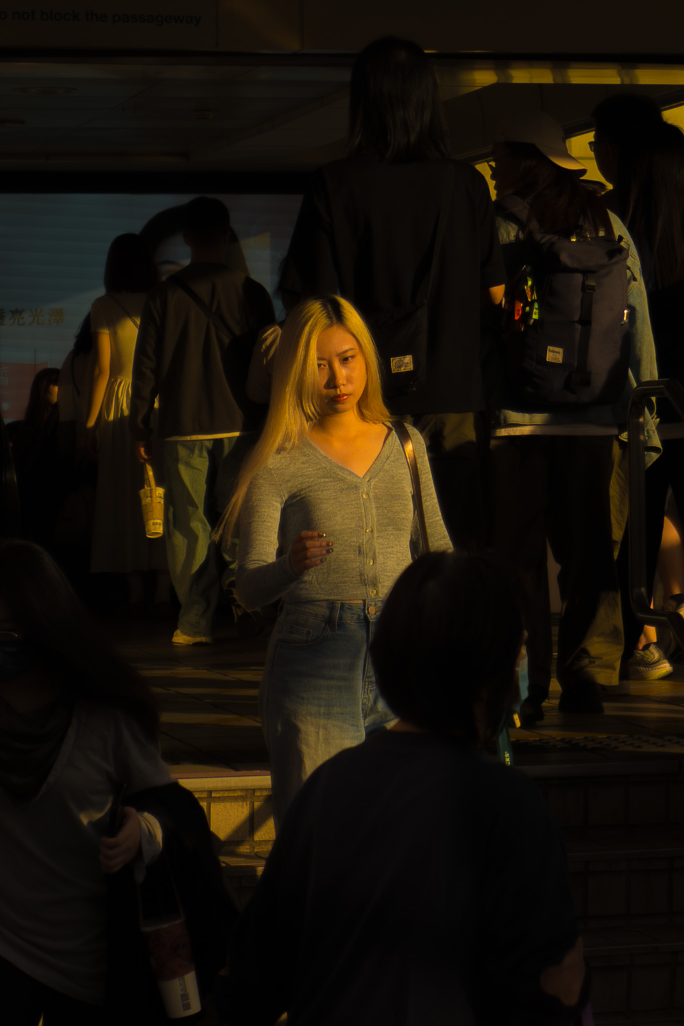 Woman standing in warm sunlight among a crowd in Taiwan